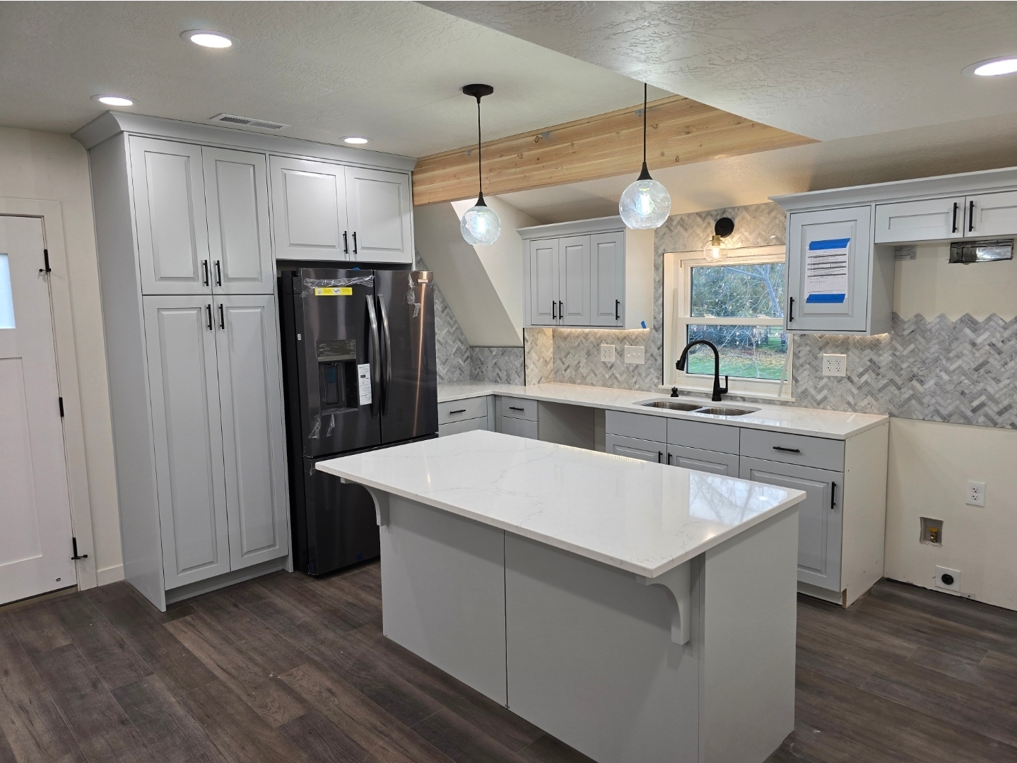 Modern white kitchen remodel with large quartz island and herringbone backsplash