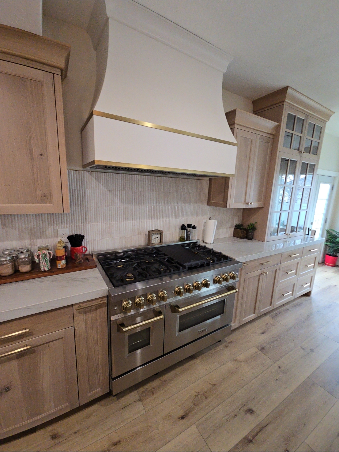 Luxury kitchen remodel with custom plaster hood, brass accents, and pro-grade range